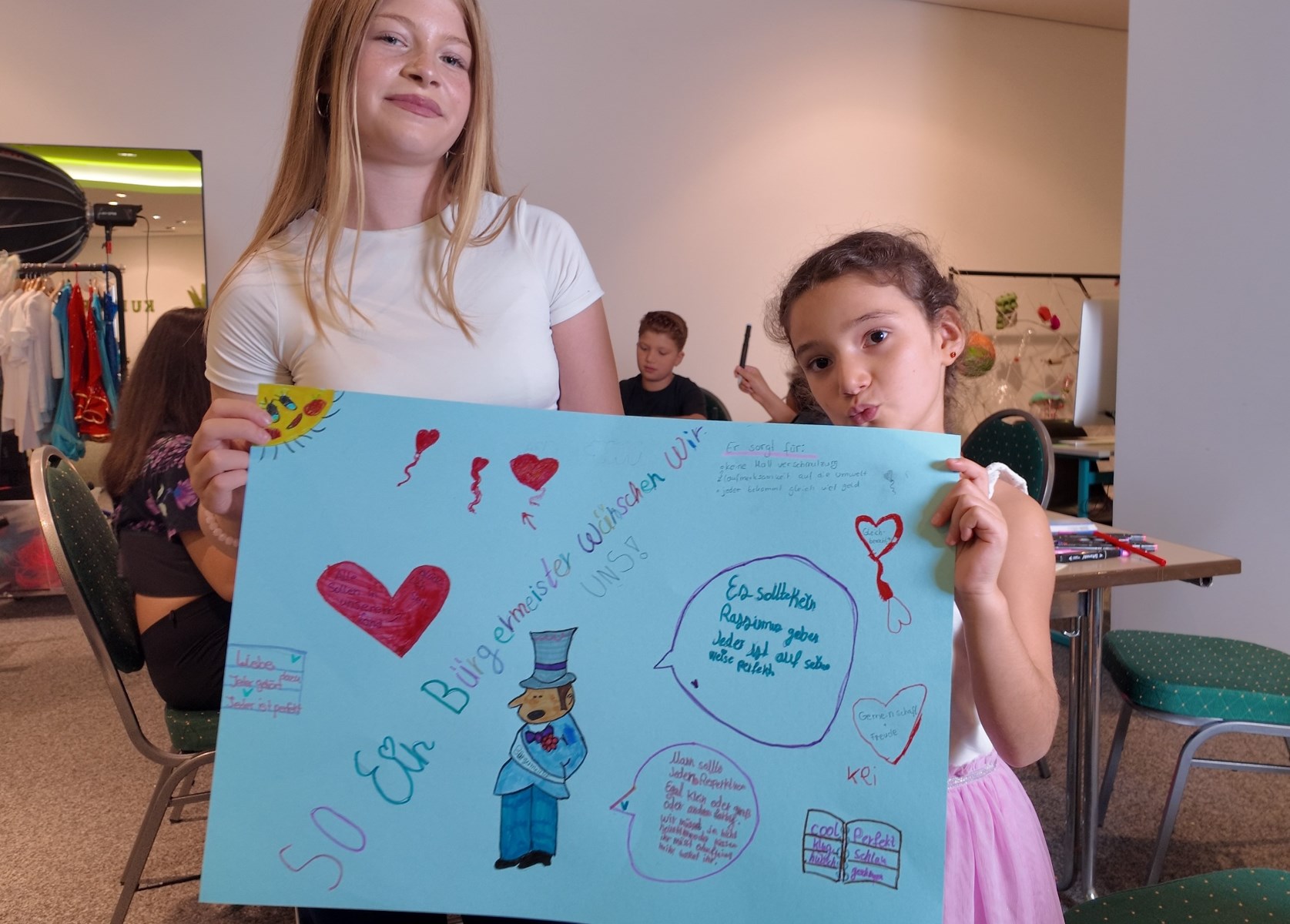 Zwei Mädchen halten ein selbst gestaltetes Plakat hoch
