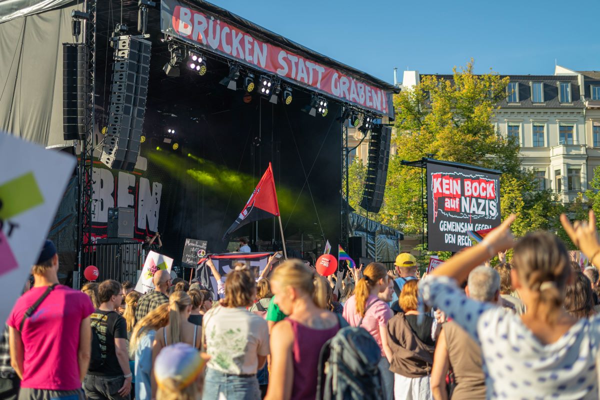 Bild einer Bühne, darauf ein Banner: "Brücken statt Gräben"