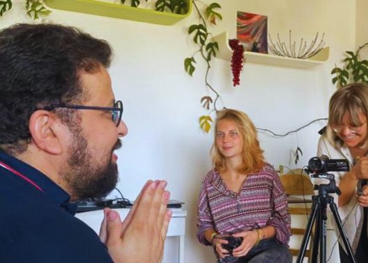 Zwei Frauen interviewen einen Mann, eine Kamera ist auf ihn gerichtet.