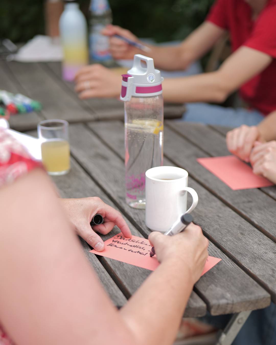 Teilnehmende der Vernetzungskonferenz sitzen zusammen und schreiben etwas auf bunte Zetteln