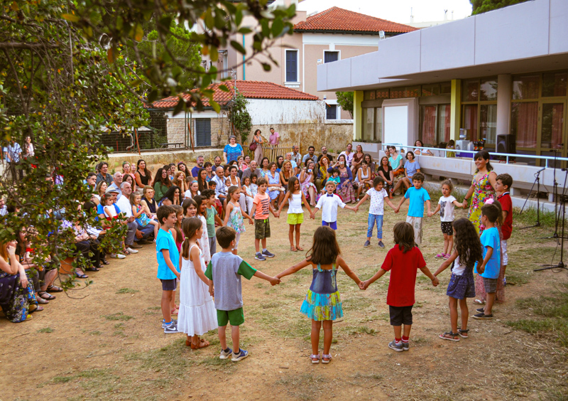 Schulkinder stehen auf dem Schulhof in einem Kreis und halten sich an den Händen