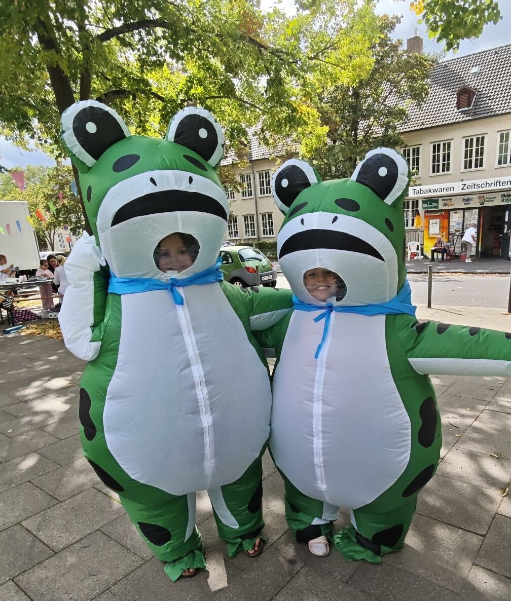 Zwei Kinder in Froschkostümen auf dem Marktplatz im Veedel
