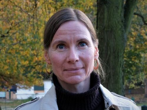 Eine braunhaarige Frau schaut ernst in die Kamera