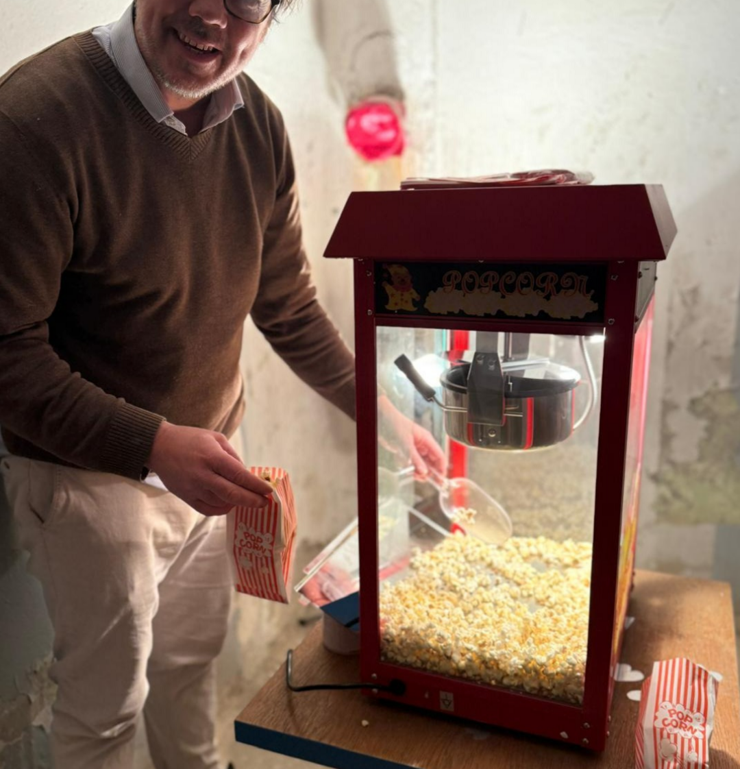 Ein lachender Mann nimmt Popcorn aus einer Popcornmaschine